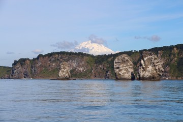 View of Tri Brata with Koryaksky volcano's top in the background. Tri Brata (Russian: Три Брата; literally: "three brothers") is a set of three rocks at the entrance to the Avacha Bay.