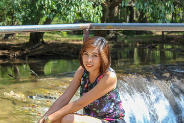 Asean woman and water in the stream is green and bright green tree at Kapo Waterfall Fores Park , Chumphon in Thailand.