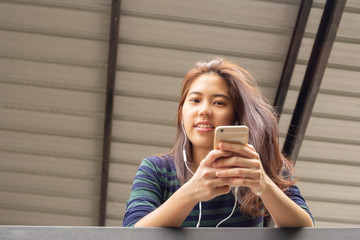 Portrait of asian 20s teenager woman listen to music with earphone.