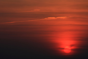 Red sun in a gray cloudy sky at sunset