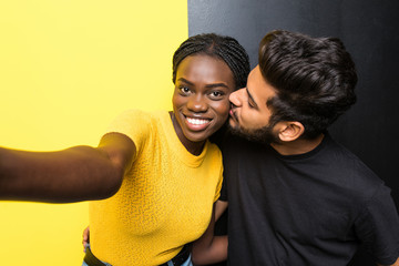 Young mixed race couple indian man kissing her african girlfriend in cheek standing isolated on...
