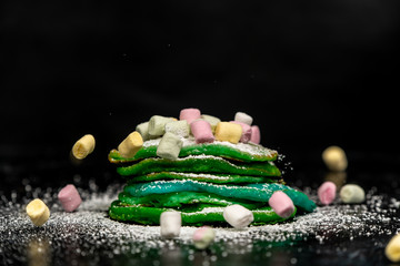 green and blue pancakes are sprinkled with powdered sugar and colored marshmallows