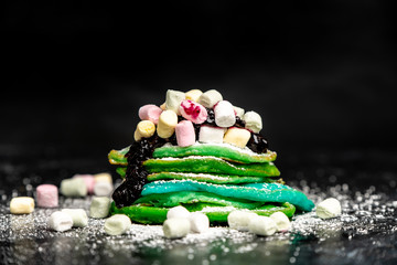 green and blue pancakes are sprinkled with powdered sugar and colored marshmallows