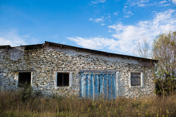 Fototapeta na wymiar abandoned farm among the tall grass, under a cloudy sky