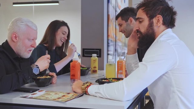 Man talking on the phone while at the lunch with his coworkers in the office canteen