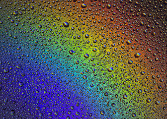 Drops of water on the glass, with the reflection of the rainbow.
