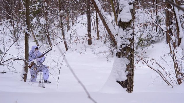 A hunter in white winter camouflage with two barrels shotgun is working in winter forest.