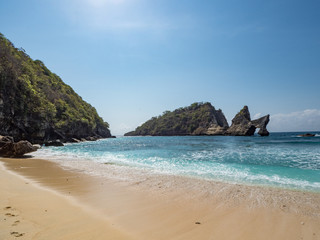 Exotic destination background with tuquoise sea water, palm trees, white sand beach and golden sun light. Warm natural colours. Top view. Atuh beach, Nusa Penida Island, Bali, Indonesia. October, 2018