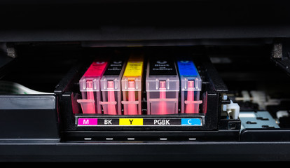 Close-up shot of a CMYK ink cartridges in a color printer. 