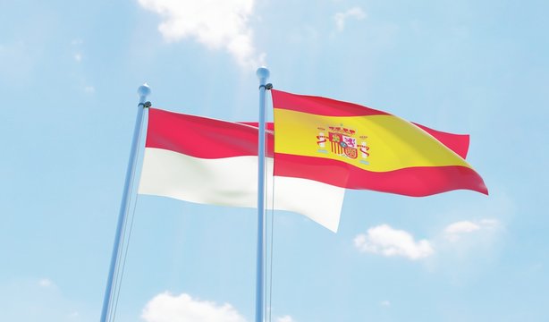 Spain and Indonesia, two flags waving against blue sky. 3d image