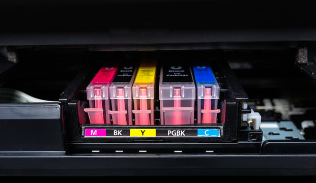 Close-up shot of a CMYK ink cartridges in a color printer. 