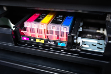 Close-up shot of a CMYK ink cartridges in a color printer. 