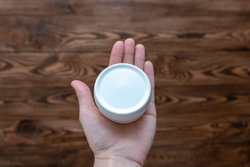 White jar of face cream in open hand