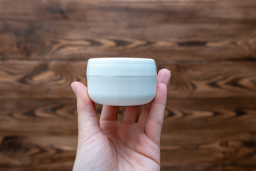 Hand holding a jar of cosmetic cream