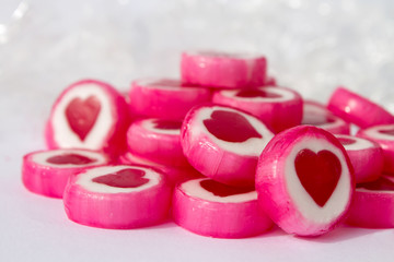 Pink and white candys with red hearts on white background