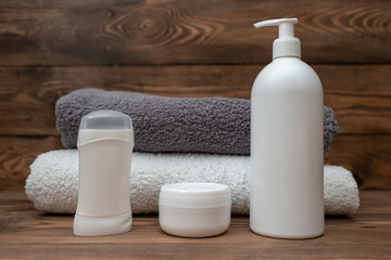 Set of cosmetics and towels on wooden background