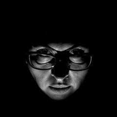Stylish portrait of attractive caucasian woman in glasses. Black and white shot, low-key lighting. Isolated on black.