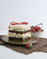 multi-layer homemade cake made of chocolate and vanilla cakes with berry fillings and jam, decorated with fresh berries and white chocolate cream