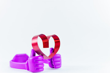 Ribbons shaped as hearts on top plastic hand on white background, valentine day concept