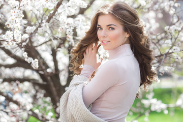 Long haired woman outdoors on spring background. Unrecognizable lady with flowers in hair. Curly haired female.