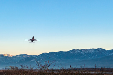 Fototapeta na wymiar Plane taking off from a runway against a blue sky and mountains