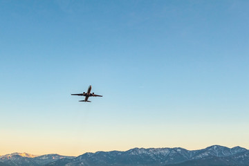 Fototapeta na wymiar Flying plane on a background of blue sky and mountains