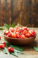 Natural fresh sweet cherry in a plate with scattered leaves around.