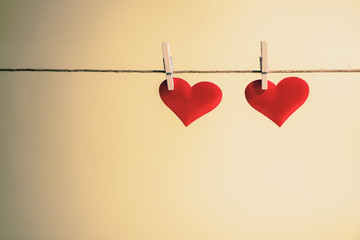 Two adorable red hearts side by side hanging from a string by wooden pegs. Romantic Valentine's Day with copy space.