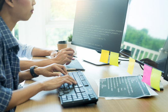 Serious busy hipster young web software developer programmer is coding or programming on a desktop computer information in modern office technologies Website design