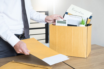 Businessmen are holding resignation document and packing personal company on brown cardboard box changing work, unemployment or resign concept
