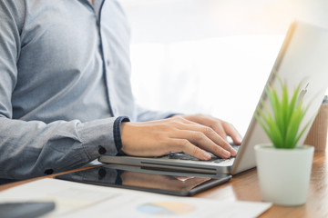 business man in suit sitting at table working on his laptop and looking at a document on the desk