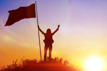 the girl with the flag on top of the mountain. against the evening sky. achieving goals, conquering the top. success.