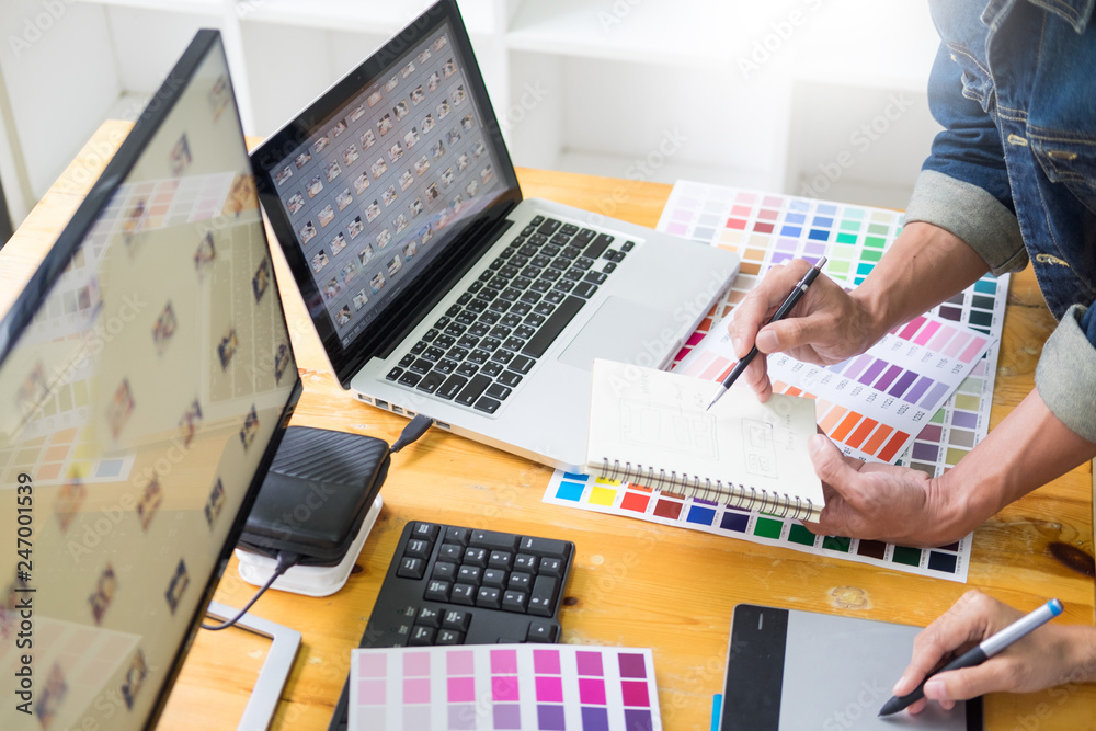 Fototapete graphic designer team working on web design using color swatches editing artwork using tablet and a 