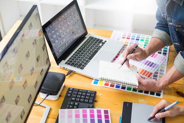 graphic designer team working on web design using color swatches editing artwork using tablet and a...