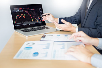 Stock traders looking at finance analysis marketing report trading stocks online in office.