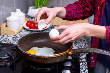Frying homemade, chicken eggs in the frying pan at kitchen at home. Cooking a healthy, protein breakfast