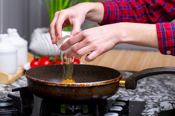 Frying homemade, chicken eggs in the frying pan at kitchen at home. Cooking a healthy, protein breakfast