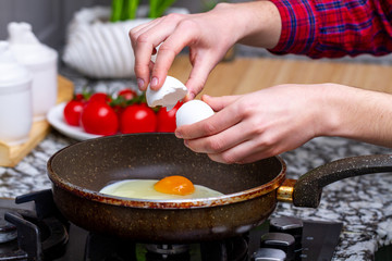 Frying homemade, chicken eggs in the frying pan at kitchen at home. Cooking a healthy, protein breakfast