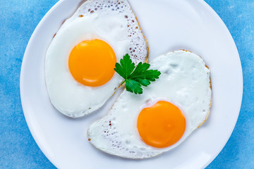 Homemade fried chicken eggs with fresh parsley on a plate for a healthy breakfast. Protein food. Top view