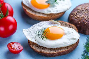 Buns with homemade, fried chicken eggs for a healthy breakfast on a blue background. Protein food. Eggs sandwiches