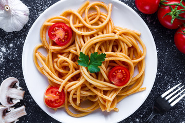 Homemade, delicious spaghetti with parsley, fresh vegetables and tomato sauce on a plate. Italian food and pasta. Top view