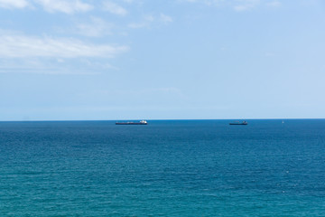 blue sea surface with small ships on the horizon