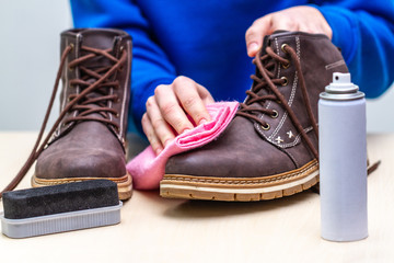 A person is cleaning men's suede casual boots with brush, rag and spray. Shoe shine and care....