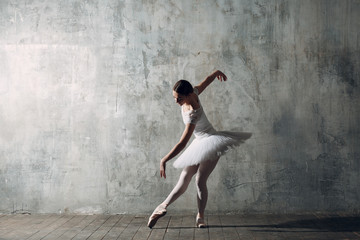 Fototapeta na wymiar Ballerina female. Young beautiful woman ballet dancer, dressed in professional outfit, pointe shoes and white tutu.