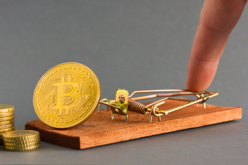 Hand presses  mousetrap with the coin bitcoin. Business concept of crypto commercial.