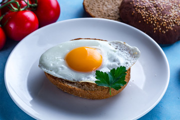 Homemade, fresh, fried chicken eggs on a plate with parsley and sesame bun for a healthy breakfast. Protein food. Eggs sandwiches.