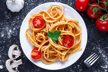 Homemade, delicious spaghetti with parsley, fresh vegetables and tomato sauce on a plate. Italian food and pasta. Top view