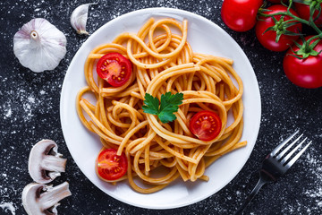 Homemade, delicious spaghetti with parsley, fresh vegetables and tomato sauce on a plate. Italian food and pasta. Top view