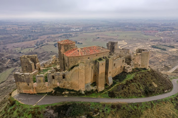 Naklejka premium Aerial view of the ruined medieval abandoned Montearagon castle, namesake of the famous kingdom on a bare mountain top near Huesca, Aragon province Spain with stormy cloudy sky