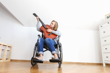 Disabled young woman in wheelchair playing the guitar.